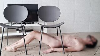 Bare fellow on the floor is crawling under stools