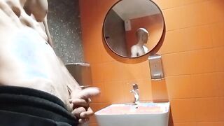 A bony boy with a clean-shaven head faps off in a shopping mall restroom