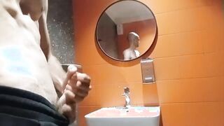 A bony boy with a clean-shaven head faps off in a shopping mall restroom
